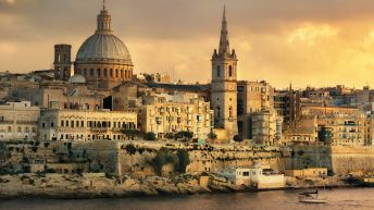 Things to do in Malta travel tips europe on a budget. Panoramic view of Valletta at sunset with Carmelite Church dome and St. Pauls Anglican Cathedral. Malta